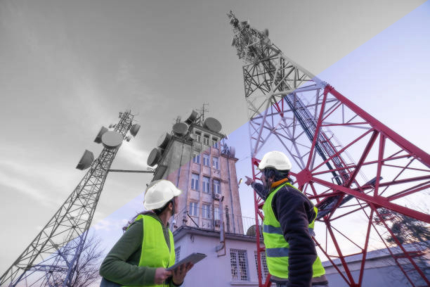 Engineers working on the field near a city Telecomunications tower, checking the condition of the Equipement. Technology and Global Business.